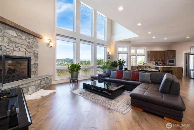 living area featuring a fireplace, wood finished floors, recessed lighting, and a towering ceiling