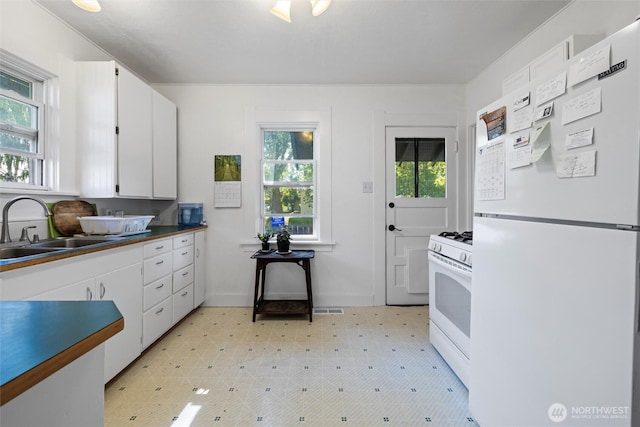 kitchen with white appliances, light floors, visible vents, a sink, and white cabinetry