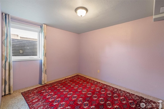 carpeted empty room featuring a textured ceiling