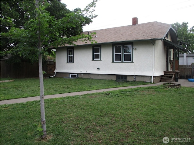 view of home's exterior with a yard, roof with shingles, a chimney, and fence