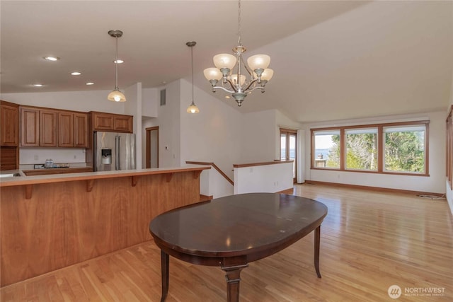 4195 Windy Cove Ln, Clinton, WA 98236 - kitchen featuring brown cabinetry, stainless steel fridge, light wood-style flooring, and vaulted ceiling