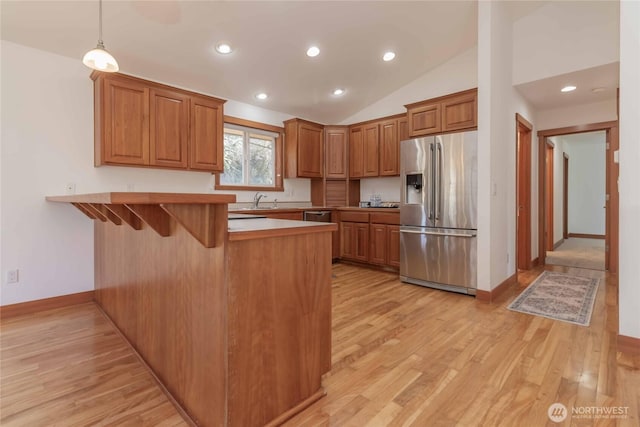 4195 Windy Cove Ln, Clinton, WA 98236 - kitchen with light wood-style flooring, a peninsula, a kitchen breakfast bar, brown cabinetry, and stainless steel appliances
