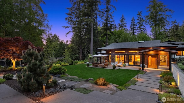 11012 Skinner Rd NE, Bainbridge Island, WA 98110 - back of property at dusk with a lawn, a patio area, and outdoor lounge area