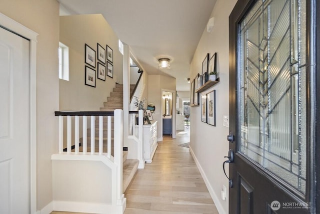 foyer entrance featuring stairs, light wood-style flooring, and baseboards