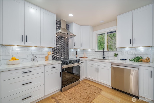kitchen with dishwasher, wall chimney exhaust hood, electric range oven, a sink, and white cabinets