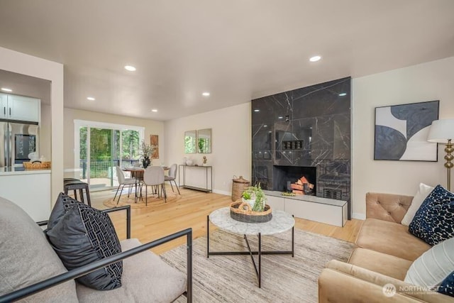 living area with wood finished floors, recessed lighting, baseboards, and a high end fireplace
