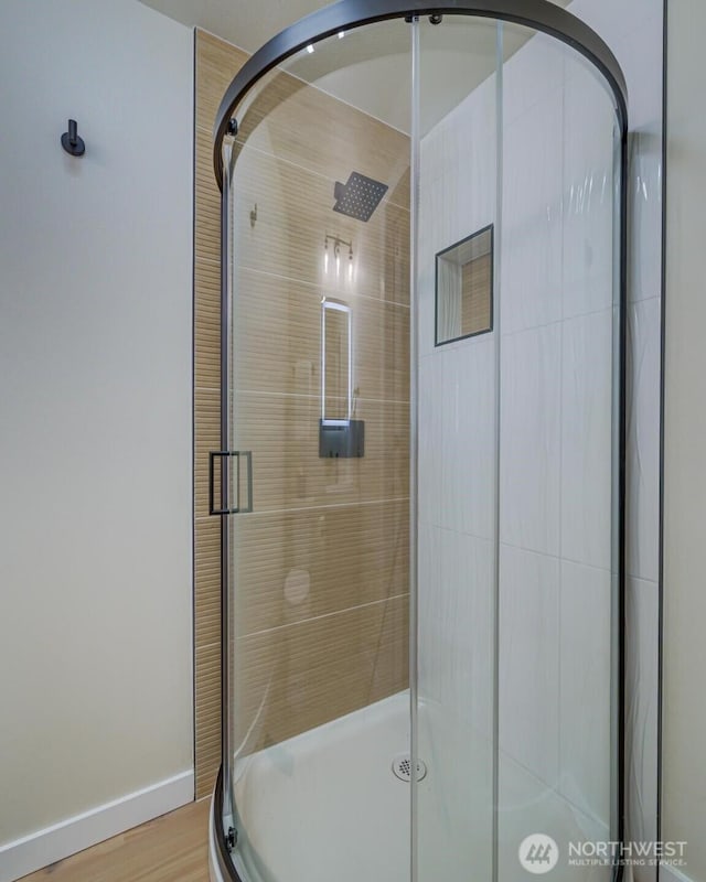 full bath with a shower stall, baseboards, and wood finished floors