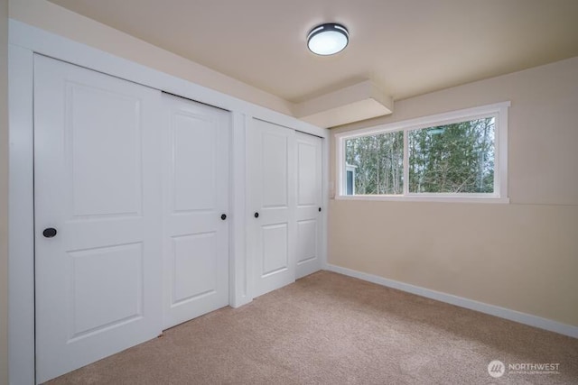 unfurnished bedroom with carpet, baseboards, and two closets