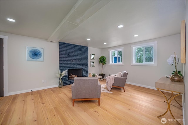 living area with baseboards, light wood finished floors, a brick fireplace, and recessed lighting
