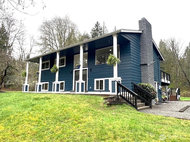 rear view of house featuring a chimney and a lawn