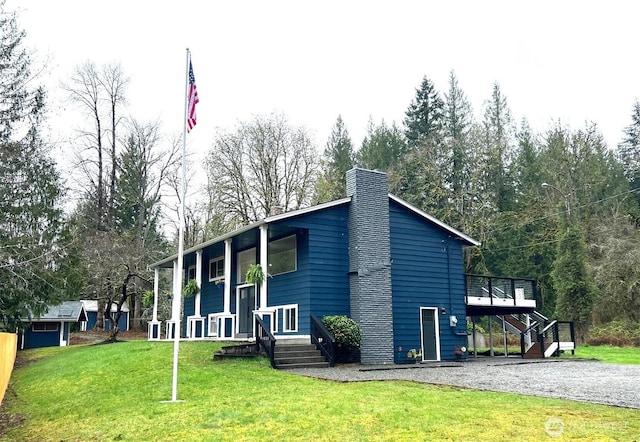 view of property exterior with a chimney, a lawn, driveway, stairway, and a wooden deck