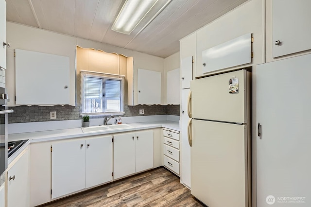 kitchen with freestanding refrigerator, a sink, light countertops, white cabinetry, and tasteful backsplash