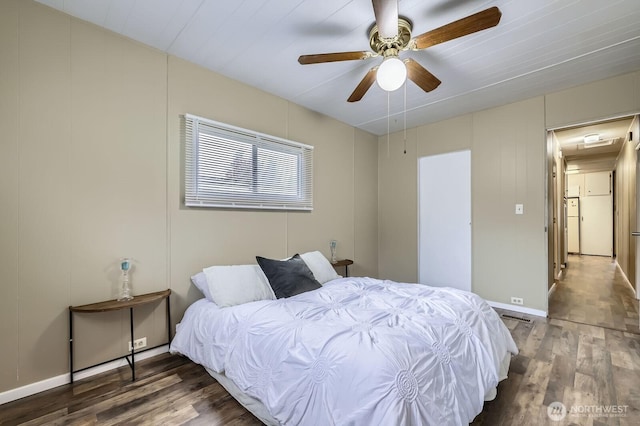 bedroom with a ceiling fan, a decorative wall, and wood finished floors