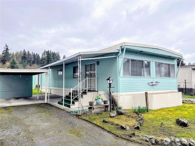 manufactured / mobile home featuring a carport and a front lawn