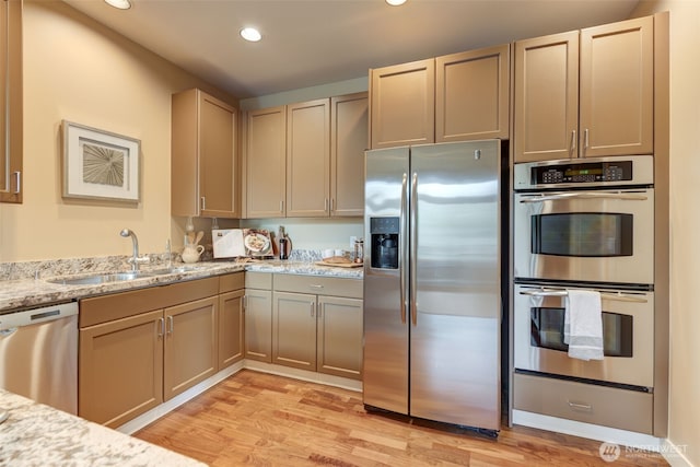 kitchen with light wood finished floors, recessed lighting, stainless steel appliances, and a sink