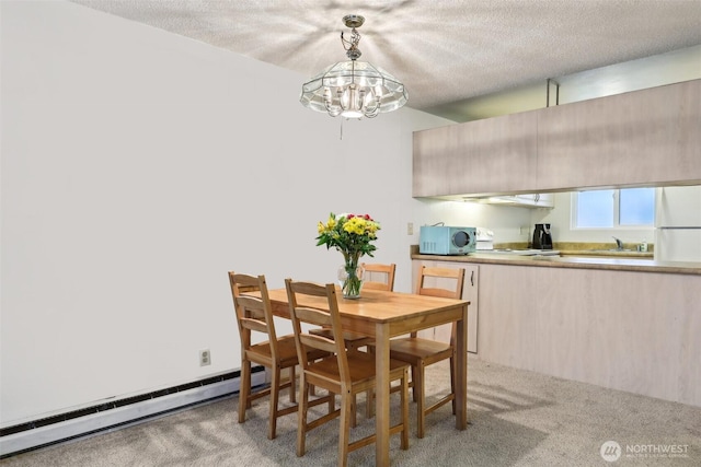 carpeted dining room featuring a baseboard heating unit, a sink, a textured ceiling, and a notable chandelier