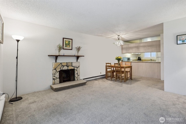 living room featuring a baseboard radiator, a chandelier, carpet floors, and a fireplace