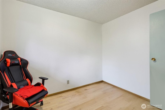 living area with baseboards, wood finished floors, and a textured ceiling