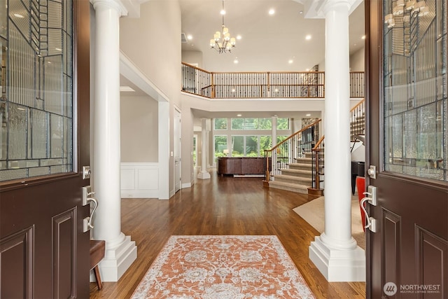 foyer with wood finished floors, stairs, and decorative columns