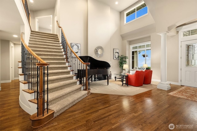 foyer featuring wood finished floors, stairs, and decorative columns