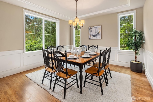 dining room with a wainscoted wall, a notable chandelier, crown molding, and light wood finished floors