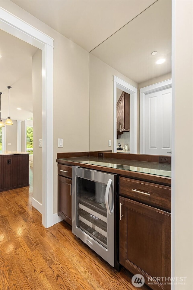 interior space with wine cooler, light wood-type flooring, and pendant lighting