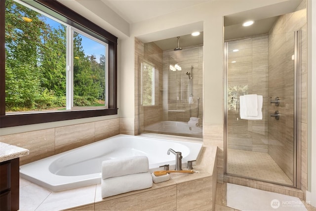 bathroom featuring vanity, a shower stall, and a garden tub