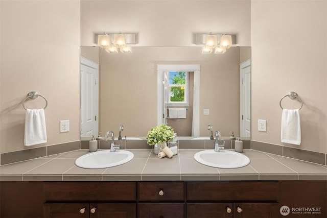 bathroom with double vanity, a notable chandelier, and a sink
