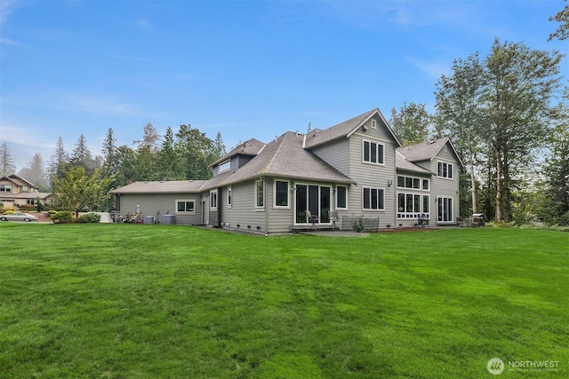 rear view of property featuring a patio area, a lawn, and a shingled roof