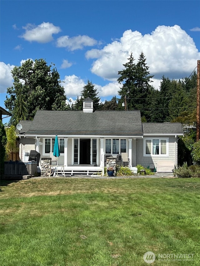 rear view of property featuring a lawn, covered porch, and a chimney