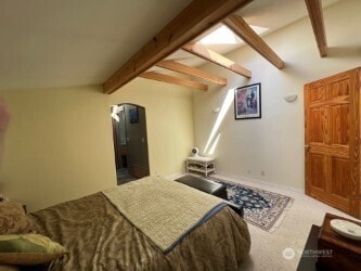 carpeted bedroom featuring lofted ceiling with beams