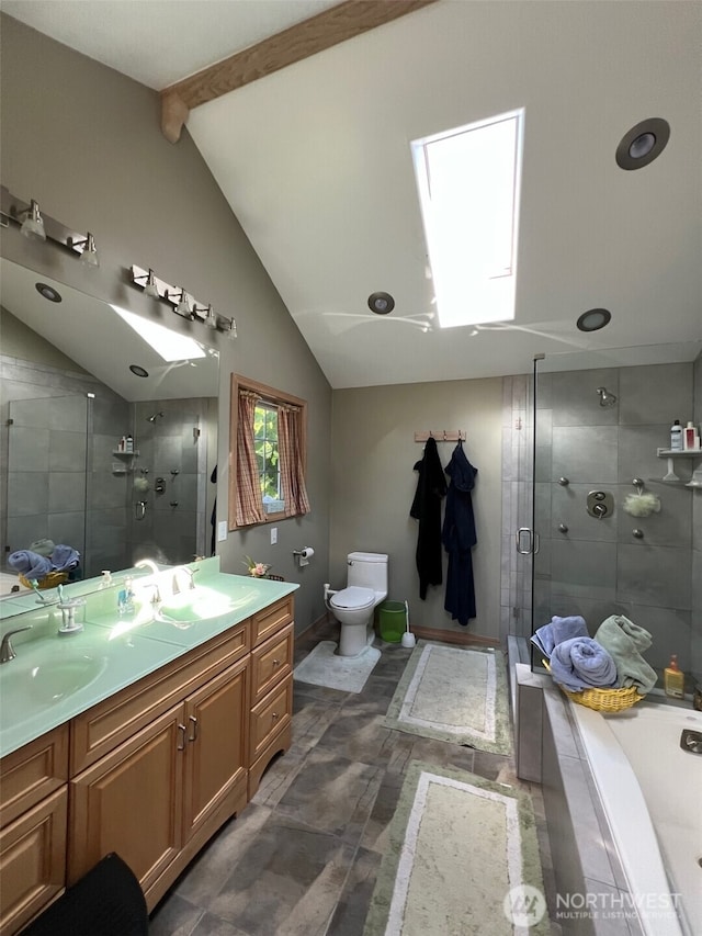 bathroom featuring a sink, vaulted ceiling with skylight, toilet, and a shower stall