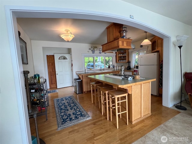 kitchen with light wood-style flooring, white appliances, a center island, and a sink