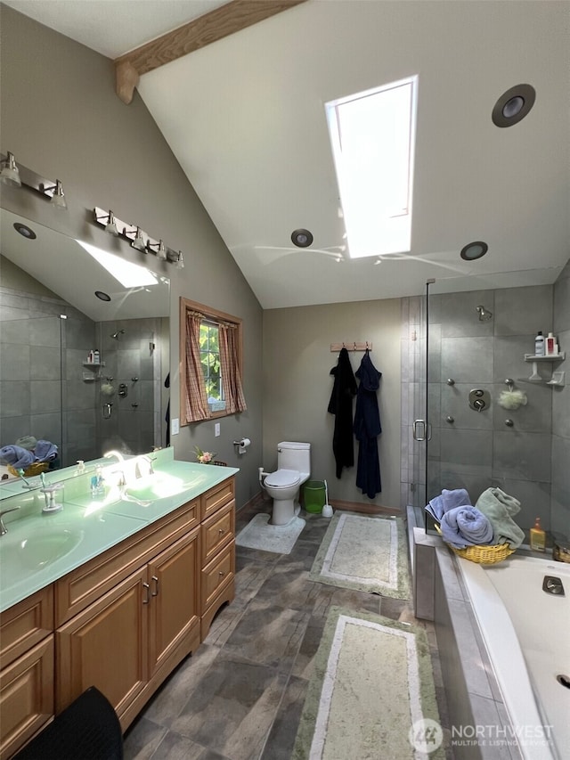 bathroom featuring a sink, vaulted ceiling with skylight, toilet, and a stall shower