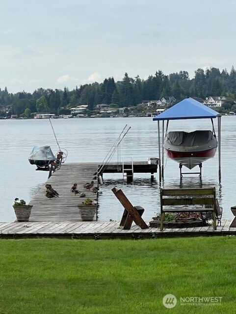 view of dock featuring a yard, a water view, and boat lift