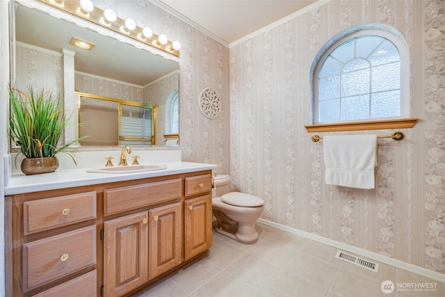 bathroom with toilet, a shower with door, visible vents, baseboards, and wallpapered walls