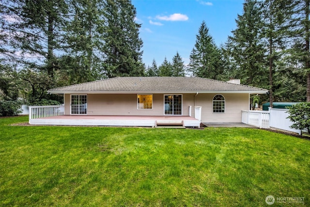 rear view of property with a chimney, a tile roof, a wooden deck, and a yard