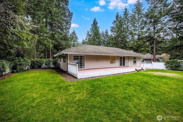 back of property with a tile roof, a deck, fence, and a yard