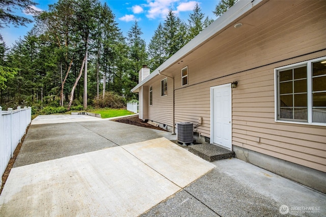 view of patio / terrace with driveway, central AC unit, and fence