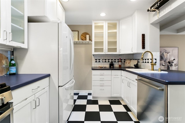4712 S Angeline St, Seattle, WA 98118 - kitchen with dark countertops, a sink, white cabinets, stainless steel dishwasher, and tile patterned floors