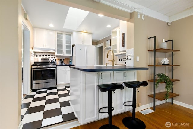 4712 S Angeline St, Seattle, WA 98118 - kitchen featuring dark countertops, dark floors, under cabinet range hood, freestanding refrigerator, and gas stove