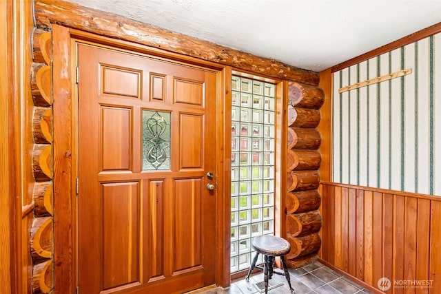 tiled entrance foyer with a wainscoted wall and log walls