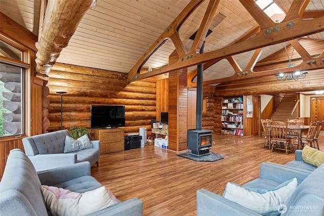 living room featuring stairs, wood finished floors, beam ceiling, a wood stove, and wood ceiling