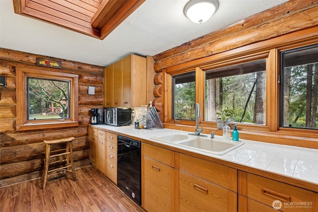 kitchen featuring dark wood-style flooring, tile countertops, a sink, and black dishwasher