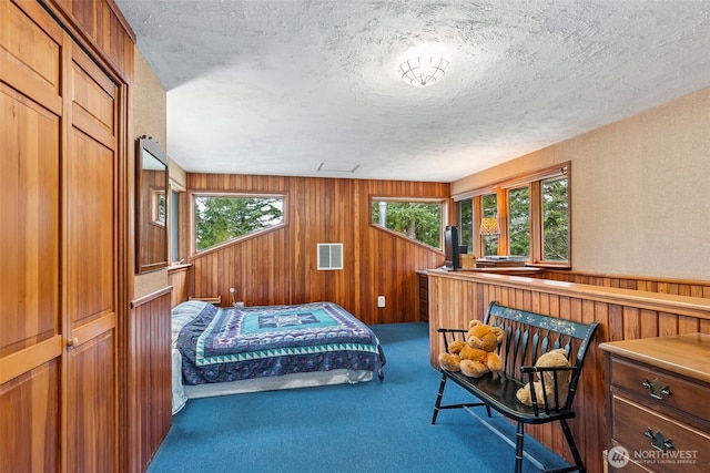 carpeted bedroom featuring multiple windows, visible vents, wood walls, and a textured ceiling