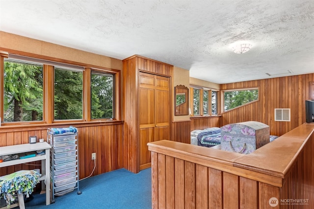 carpeted bedroom featuring visible vents, multiple windows, and wooden walls