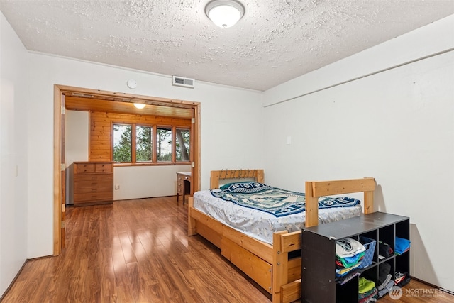 bedroom with visible vents, wood finished floors, and a textured ceiling