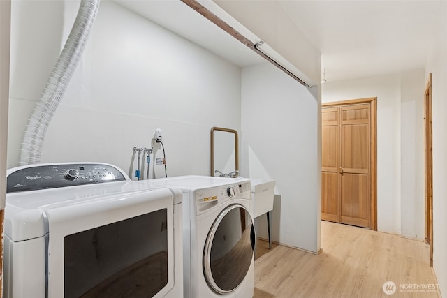 clothes washing area featuring washing machine and dryer, laundry area, and light wood finished floors