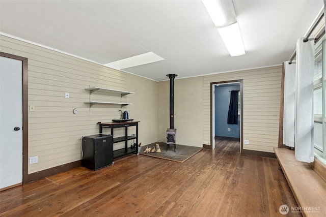 living room with wooden walls, a wood stove, and wood-type flooring