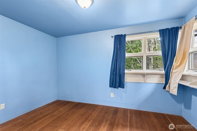unfurnished room featuring baseboards and wood finished floors